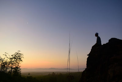 Silhouette man standing on mountain against sky during sunset