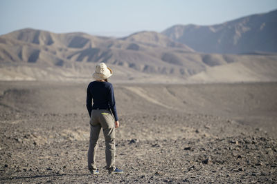 Rear view of mid adult woman standing on landscape