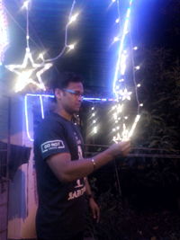 Young man holding light painting at night
