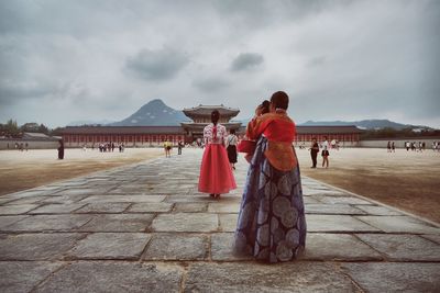 People at gyeongbokgung against cloudy sky