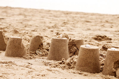 Hay bales on sand at beach against sky