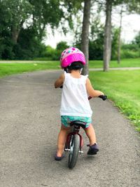 Full length rear view of girl riding bicycle on road