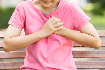 Midsection of woman holding pink while standing outdoors