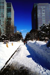 People on snow covered buildings in city