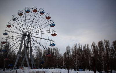 Low angle view of ferris wheel against sky during winter