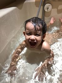 Portrait of naked boy smiling in bathtub