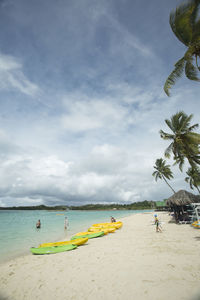 Boats moored at beach against cloudy sky