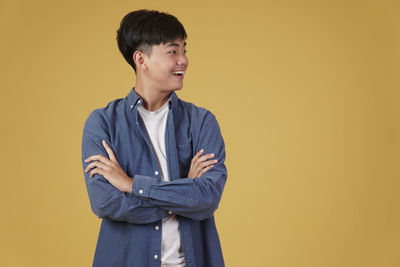 Young man looking away against yellow background