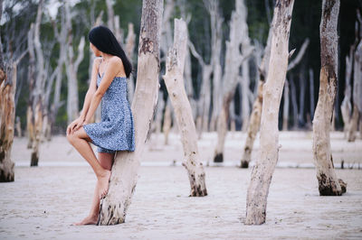 Woman standing on tree trunk