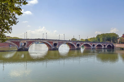 Arch bridge over river against sky