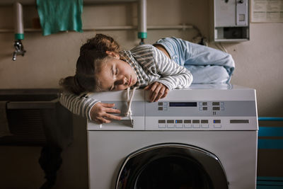 Teenage girl using common laundry to save resources and money. sustainability and environment care