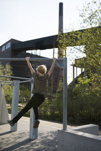 Full length of boy hanging on pole in city