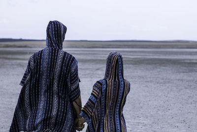 Rear view of couple holding hands while standing on field