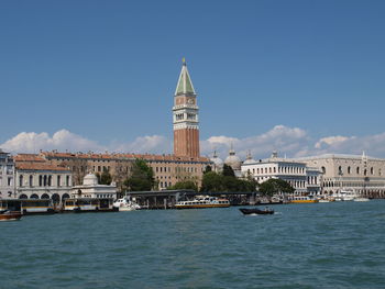 View of buildings by canal against sky in city