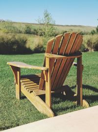 Empty chair on field against sky