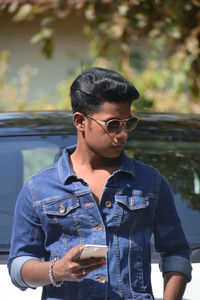 Portrait of young man standing against car