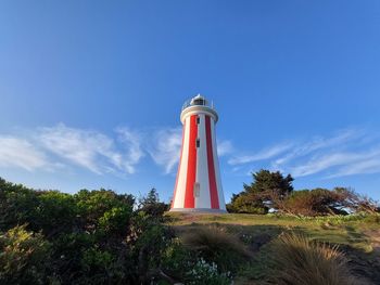 Low angle view of lighthouse by building against sky