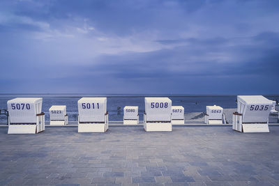 Hooded chairs on beach against sky