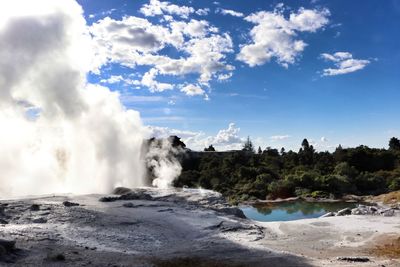 Scenic view of waterfall against cloudy sky