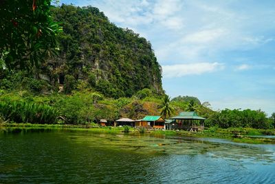 Scenic view of lake by trees and building against sky