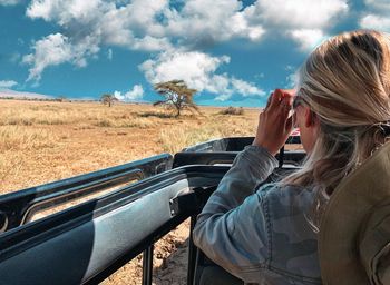 Woman sitting in car against sky