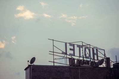 Low angle view of bird perching on pole against sky