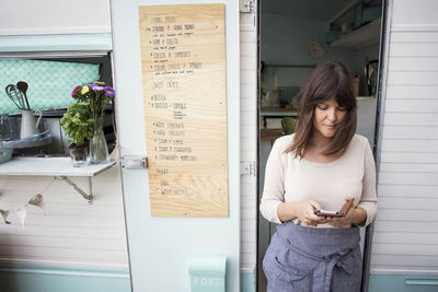 Female owner using smart phone outside food truck