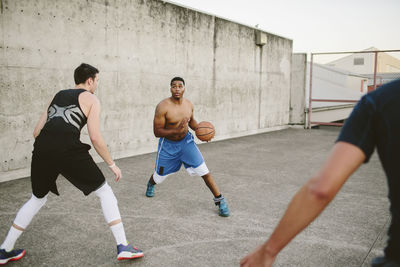 Male friends practicing basketball in court