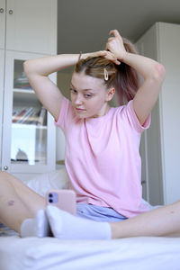 Very cute girl aged 15-18 sits on the bed