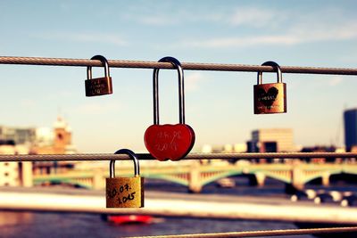 Love padlocks on metal cables against sky