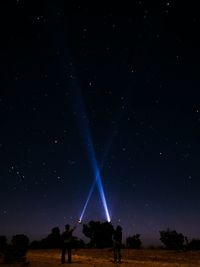 People with flashlights on field against sky at night