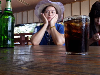 Portrait of a woman drinking glass on table