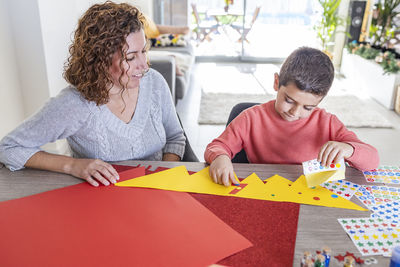 Mother and son making crafts at home with cardstocks and stickers