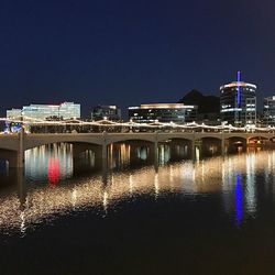 Illuminated bridge over river in city at night