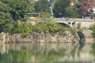 Arch bridge over river against trees