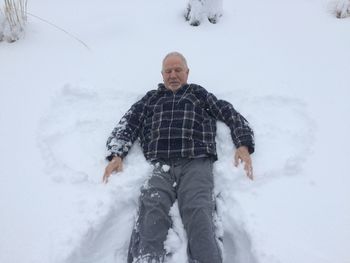 High angle view of senior man lying on snow field