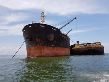 Rusty ship in sea against sky