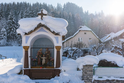 The mountain chapel with cross covered with wooden shingle. snow-capped mountains, trees.