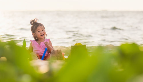 Portrait of cheerful girl sitting at beach