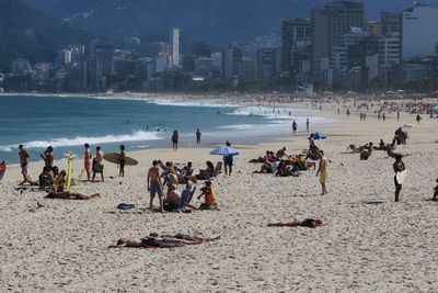 People at beach against sky in city