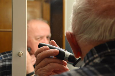 Senior man shaving his face in bathroom