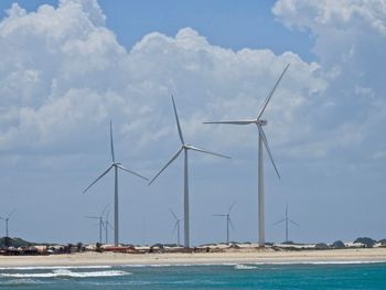 Wind turbines on beach against sky