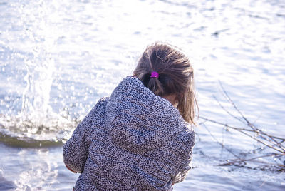 Rear view of girl playing with water on sunny day