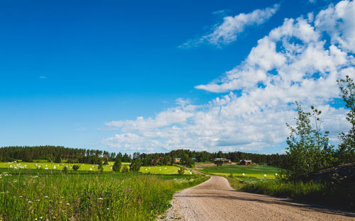 Road amidst field against sky