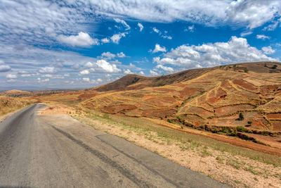 Road amidst field against sky