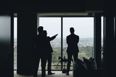 Rear view of silhouette man standing against window