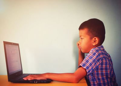 Side view of boy using laptop at home