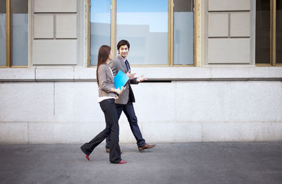 Business people talking while walking on footpath