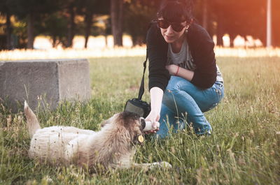 Woman playing with dog on grassy field