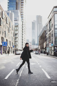 Full length of woman walking on street against buildings in city